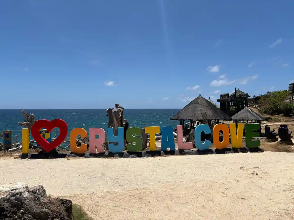 the coloured Crystal Cove letters standing on the sand with huts behind