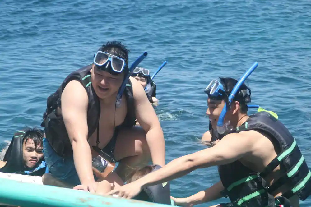 guests in life vests and masks helping each other at the boat ladder