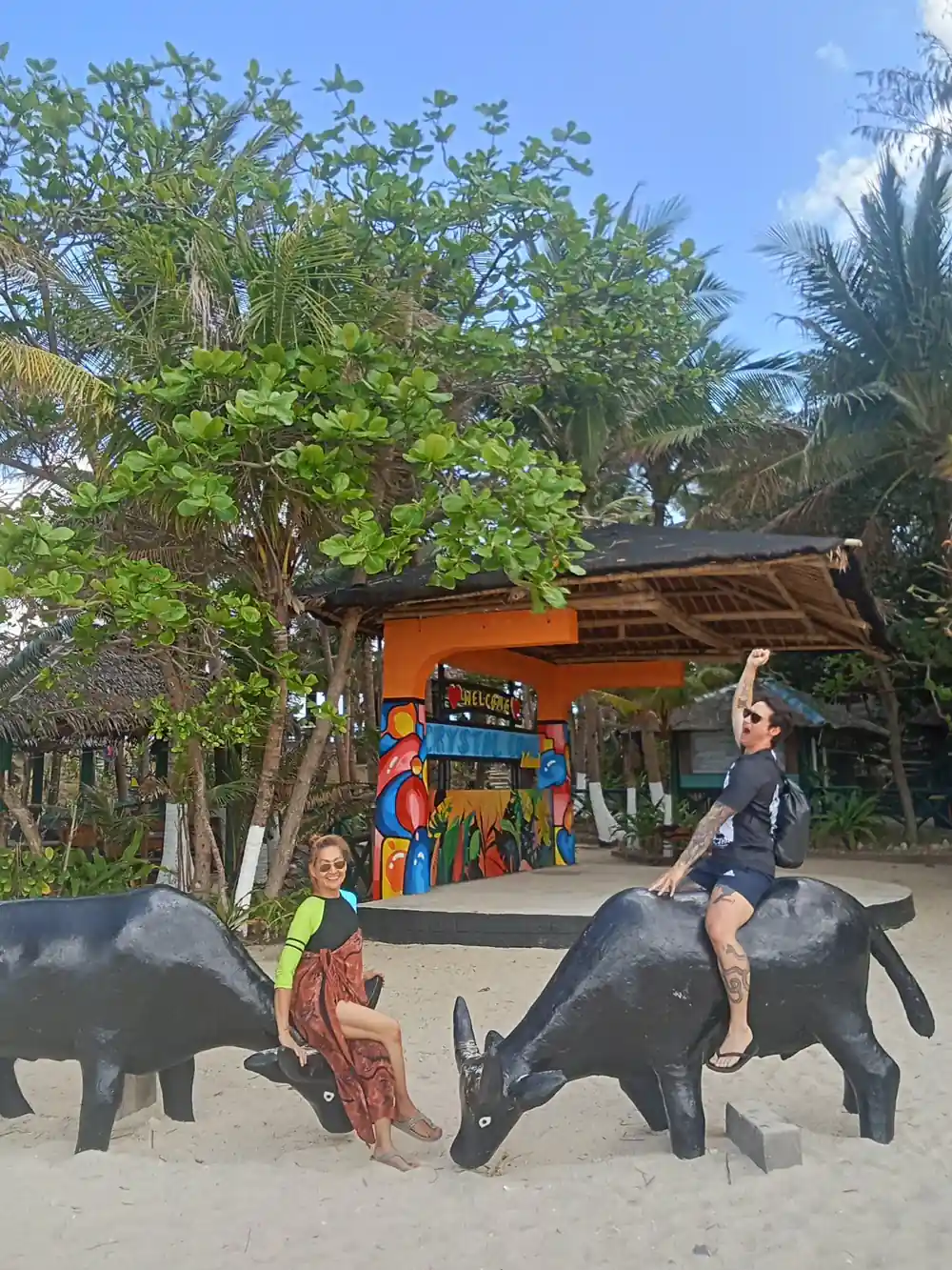 guests posing on carabao statues at a beachside entrance