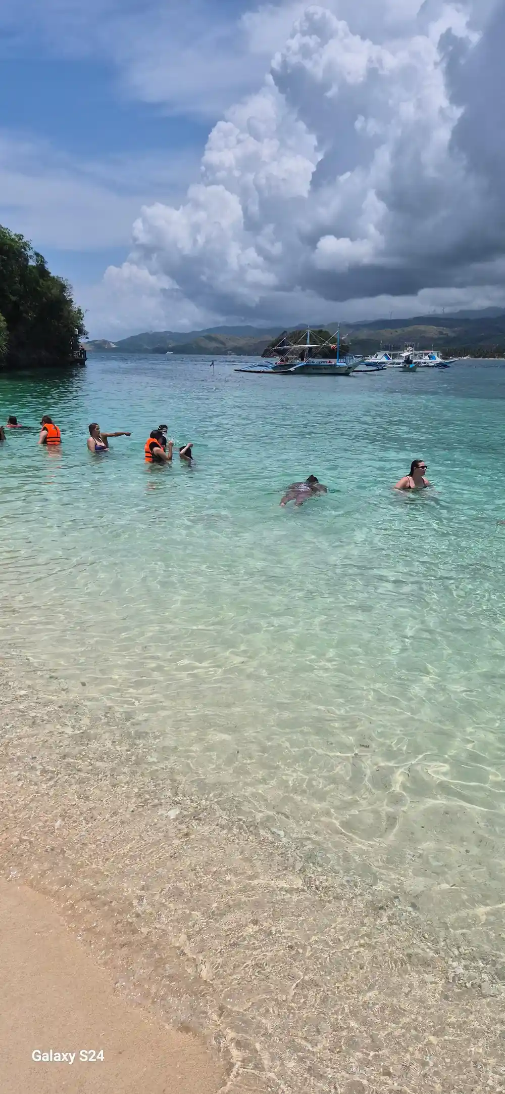 guests standing in the shallows near the moored boats