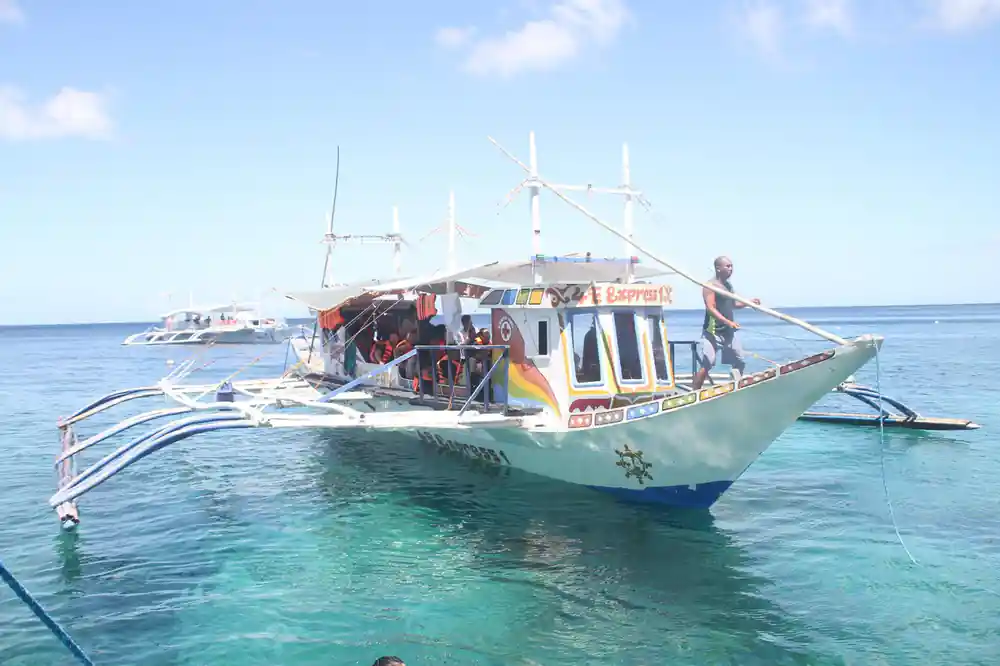 the outrigger boat with its bamboo arms moored in shallow turquoise water
