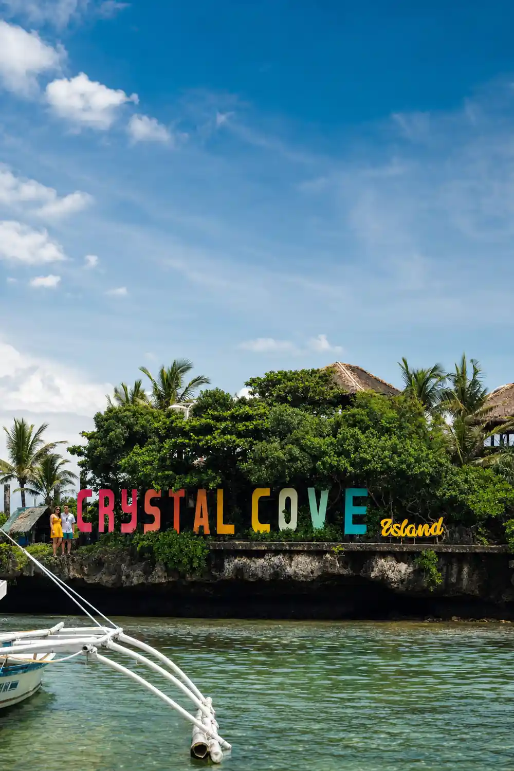 the painted Crystal Cove Island sign set into the greenery above the shore