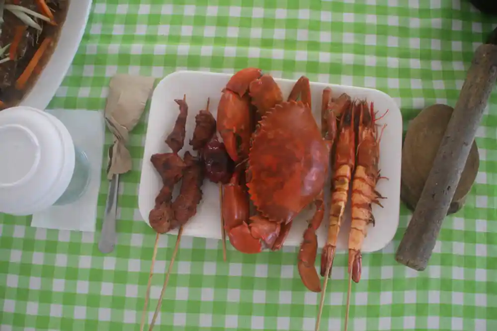 a platter of crab, prawns and grilled skewers on a checked cloth