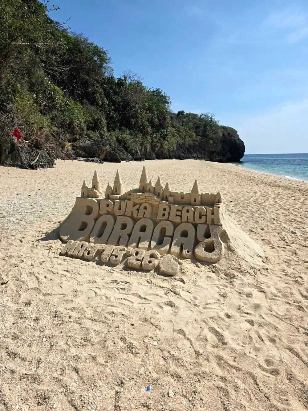 a Puka Beach Boracay sand sculpture with the shoreline behind