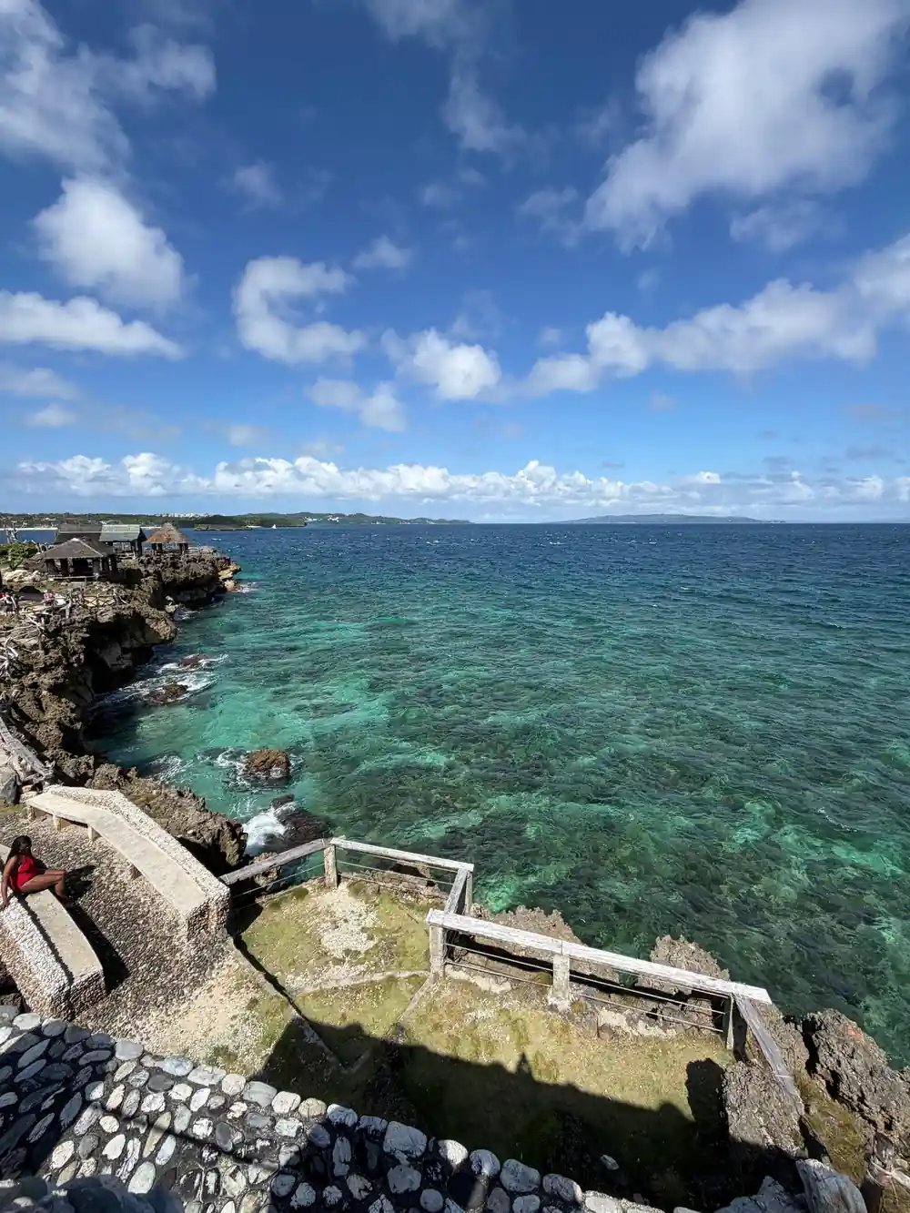 the rocky shoreline of a cove with clear green water over reef