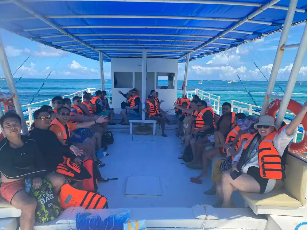 rows of guests in orange life vests seated under the boat canopy