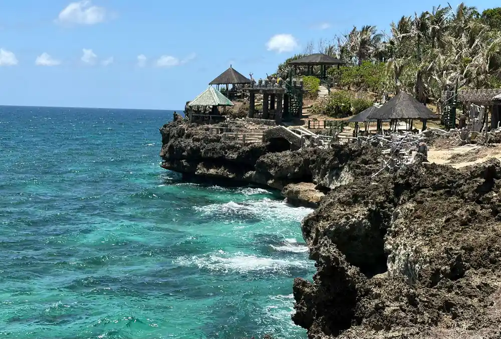 thatched pavilions on the rocks above clear turquoise water